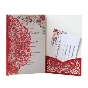 Macro view of laser-cut lace pattern and red glitter finish on wedding invitation