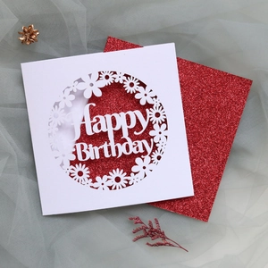 Detailed laser-cut daisy hollow pattern on white birthday card with red glitter insert