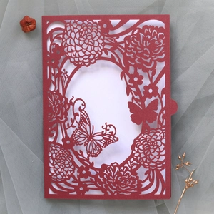 Detail of laser-cut burgundy invitation with elegant butterfly and floral patterns