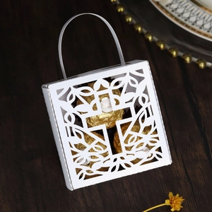 Close-up of hollow laser-cut white wedding favor box holding three chocolate pieces