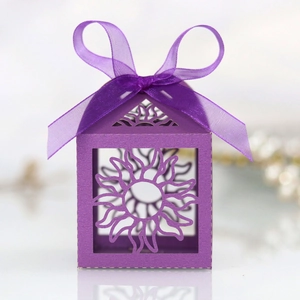 Macro shot of purple laser-cut gift box with sun pattern and elegant silk ribbon bow