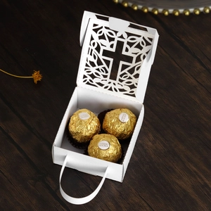 Macro detail of laser-cut cross gift box in white paper with golden chocolates