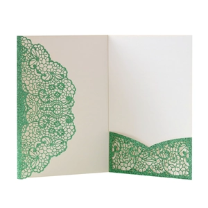 Detail view of laser-cut ivory invitation with green glitter floral vine patterns