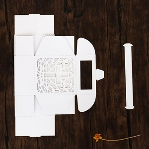 Flat lay of unassembled white hollow cross candy box with laser-cut vine patterns