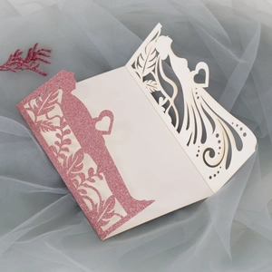 Λεπτομέρεια προσκλητηρίου γάμου laser-cut με σιλουέτα νύφης-γαμπρού και χαρτί με χρυσόσκονη