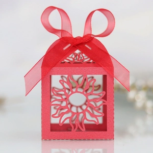 Detail of red hollow laser-cut favor box with sun pattern and elegant ribbon bow