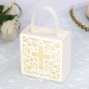 Detail of cream laser-cut hollow cross candy box with intricate floral vine patterns