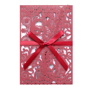 Detailed laser-cut floral pattern on elegant dark red wedding invitation with satin ribbon