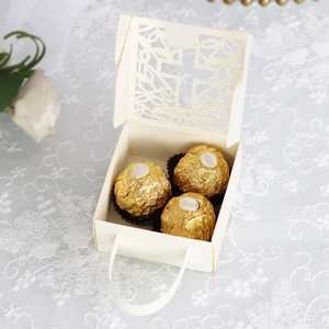 Detail of hollow cross wedding favor box in cream with laser cut design and ribbon handle