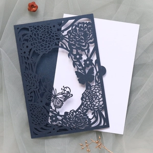 Macro shot of navy laser-cut invitation card with floral patterns and butterfly details