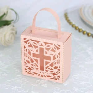Detail view of light pink laser-cut paper gift box with hollow vine pattern and cross