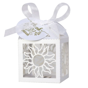 Close-up of white laser-cut hollow sun pattern gift box with ribbon and thank you card