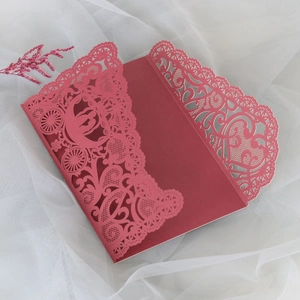 Detailed close-up of dark red laser-cut wedding invitation with pumpkin carriage lace pattern