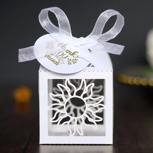 Detail of laser-cut sun pattern gift box with white silk ribbon and thank you tag