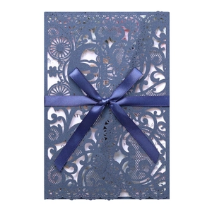 Detail of laser-cut lace wedding invitation with elegant ribbon and floral carriage design