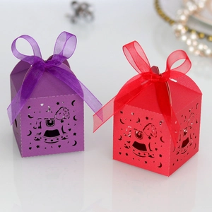 Detail of laser-cut rocking horse candy boxes in purple and red with organza ribbons
