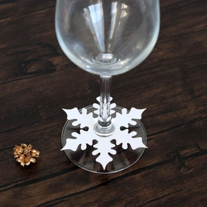 Macro detail of white snowflake place cards for wine glass stem decoration on a wooden table