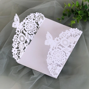 Macro view of laser-cut white wedding card with hollow floral and butterfly patterns