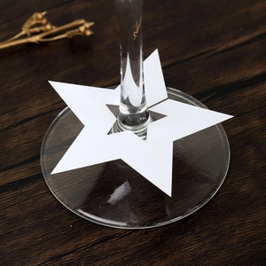 Tarjetas de mesa con forma de estrella blanca para copas en fondo de madera