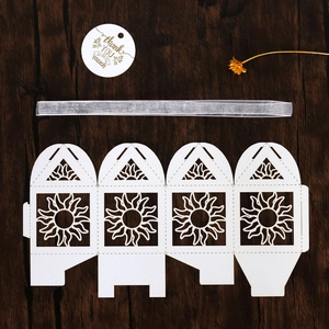 Flat lay of laser-cut sun hollow paper candy box with silver ribbon and thank you tag
