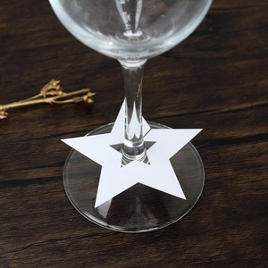 Vista detallada de tarjetas de lugar de papel blanco con forma de estrella para copas de vino