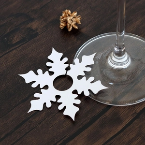 Macro detail of white snowflake place cards with laser cutouts for wine glass stems