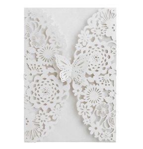 Macro detail of laser-cut floral patterns and 3D butterfly on white wedding invitation