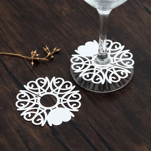 Detailed view of white laser-cut paper heart decorations for wine glass stems at weddings
