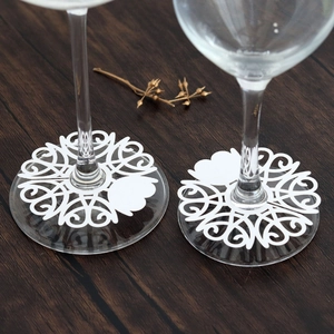 Detailed view of white laser-cut heart paper glass markers on wine glass stems