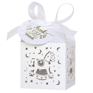 Detail of white laser-cut candy box with rocking horse pattern and silk ribbon