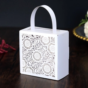 Close-up of intricate laser-cut lace floral patterns on white wedding gift box