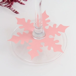 Pink snowflake-shaped paper wine glass place cards for festive Christmas table setting