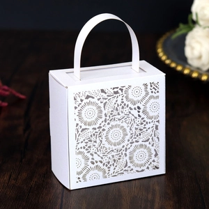 Close-up of laser-cut hollow daisy patterns on a white paper wedding gift favor box