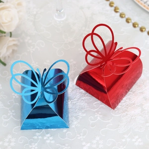 Close-up of laser-cut butterfly gift boxes in metallic blue and red on lace cloth