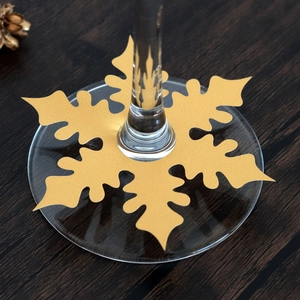 Golden snowflake wine glass name card for festive table decoration on dark wood background