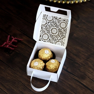 Macro shot of white laser-cut floral pattern wedding gift box on dark wooden background