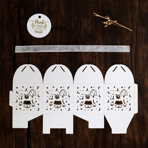 Detail of white laser-cut rocking horse candy box with silver ribbon and thank you tag