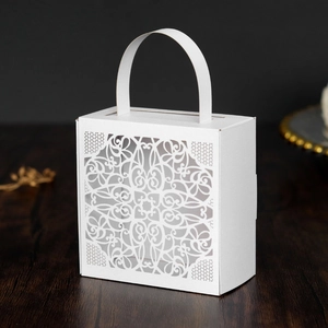 Close-up of laser-cut lace pattern and handle on white hollow paper wedding gift box