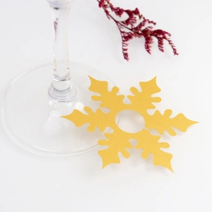 Detail of a golden glitter snowflake place card on a wine glass for Christmas table settings