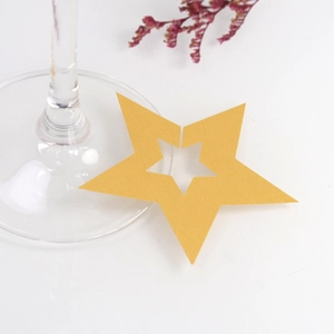 Detalle de tarjetas de mesa estrella dorada para copas de vino en decoración de fiesta