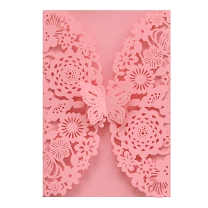 Detail of pink laser-cut wedding invitation featuring intricate floral patterns and a 3D butterfly