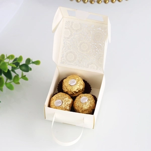Macro detail of laser-cut lace floral pattern on cream wedding favor gift box with handle