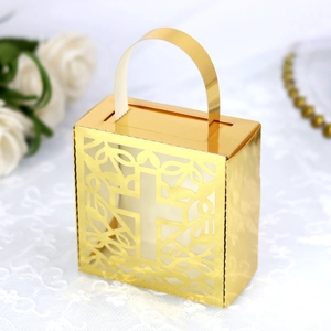 Close-up of golden wedding candy box with laser-cut cross and white lace background
