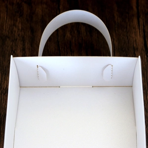 Detailed macro view of white matte wedding lace favor box with elegant handle design