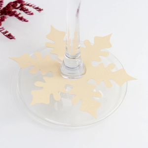 Close-up of snowflake shaped wine glass place cards with a slot for stems on a white table