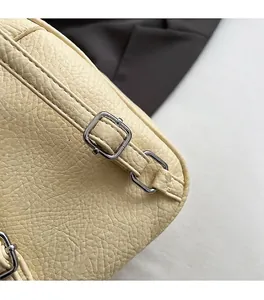 Détail du sac à dos en cuir crème avec texture litchi et boucle en métal argenté