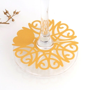 Macro shot of gold laser-cut heart seat cards placed on the base of clear wine glasses