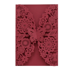 Close-up of laser-cut burgundy wedding invitation featuring intricate butterfly floral pattern