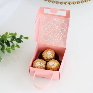 Close-up of pink laser-cut hollow pattern on a wedding candy gift box with handle