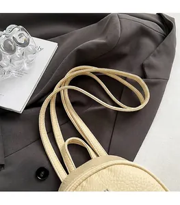 Détail d'un sac à dos en cuir crème avec texture grainée et fines bretelles souples